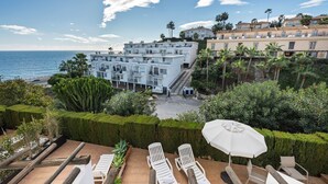 A resort with a pool area, lounge chairs, and a view of the sea. - AS MDS 310 in Mijas Costa (Mijas)