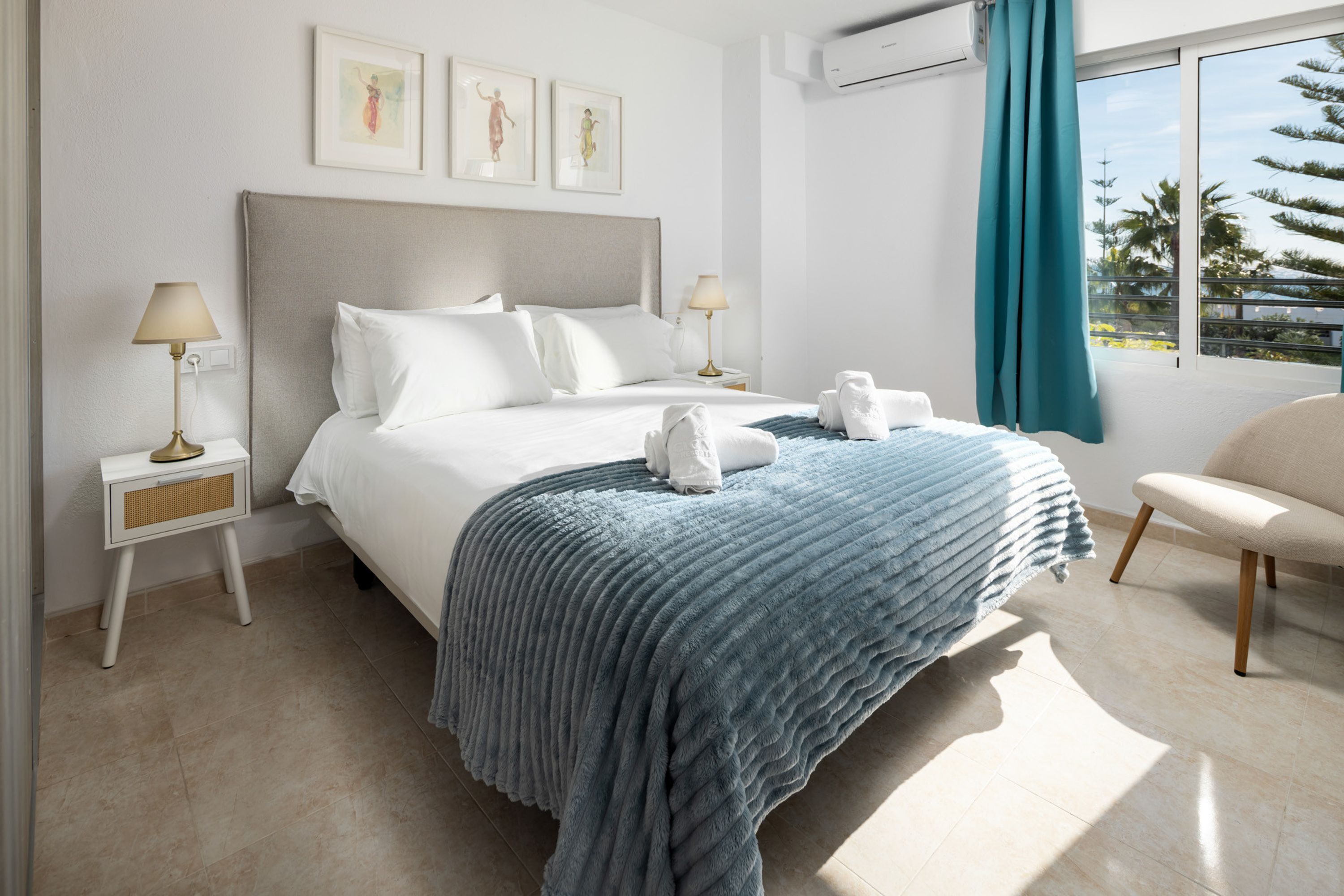 A modern hotel bedroom with a large bed, two bedside tables with lamps, a view of the outdoors, and a window with a curtain.