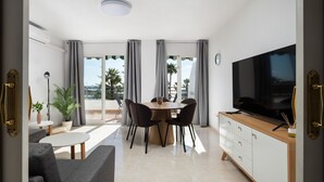 A modern living room with a dining area, a TV, and a balcony with a view. - AS MD 9B1 in Mijas Costa (Mijas)