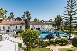 A resort with a swimming pool, palm trees, and a clear blue sky. - AS MD 9B1 in Mijas Costa (Mijas)