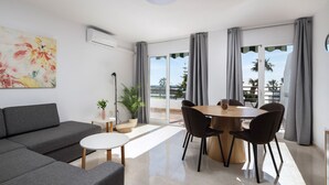 A modern living room with a sofa, a dining table with chairs, a potted plant, and a large window with curtains. - AS MD 9B1 in Mijas Costa (Mijas)