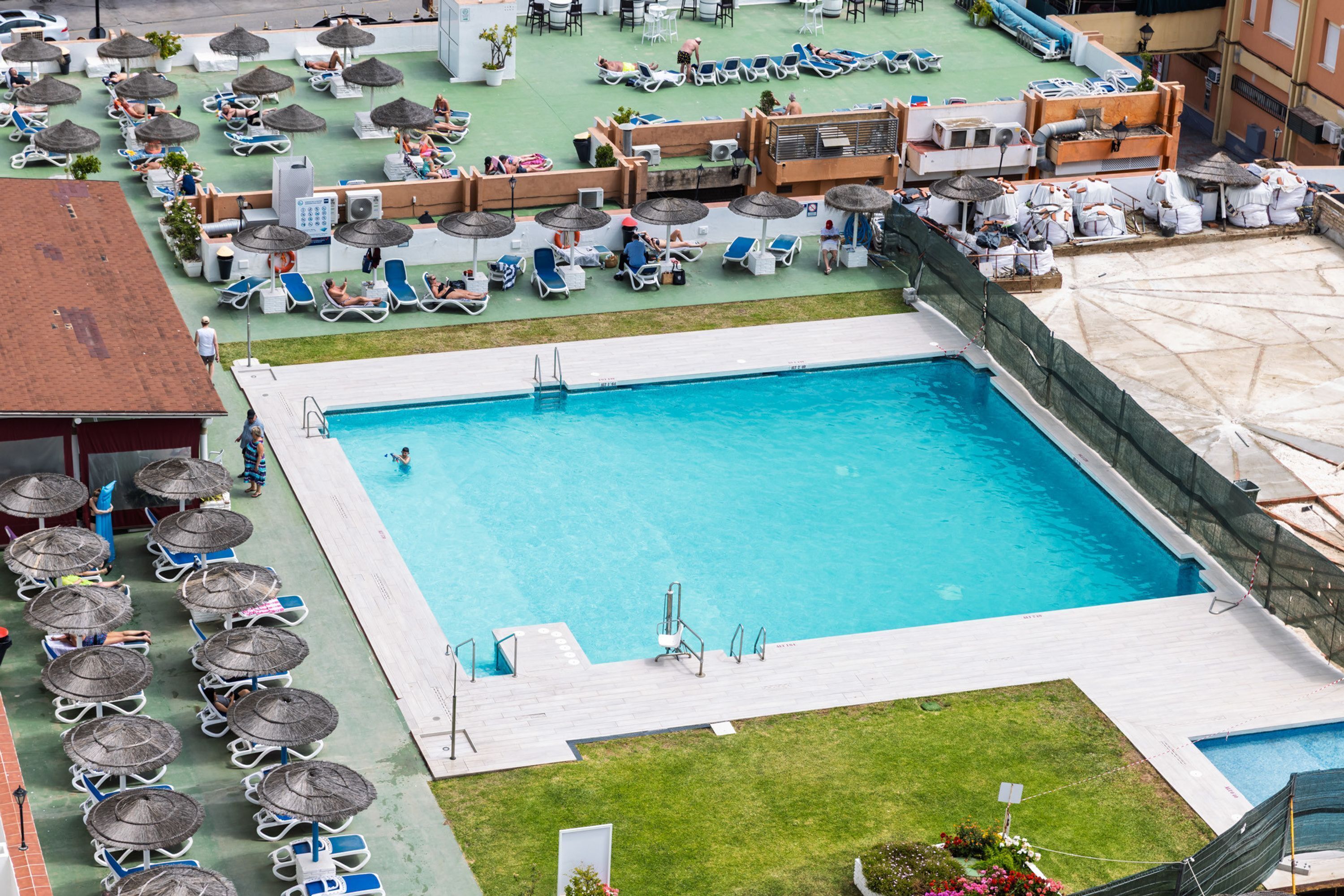 Área de piscina no terraço, com espreguiçadeiras, guarda-sóis e uma piscina.