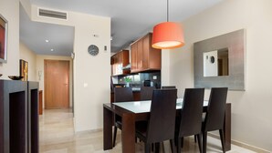 A modern kitchen with wooden cabinets, a dining table with chairs, a pendant light, and a large mirror on the wall. - AS MM A09 in Mijas Costa (Mijas)