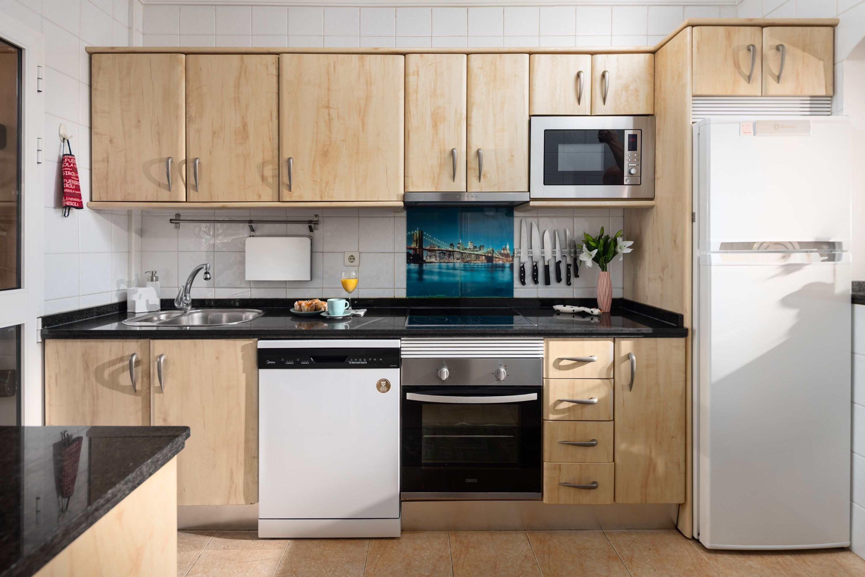 Una cocina moderna con armarios de madera, lavavajillas, horno, microondas y refrigerador.