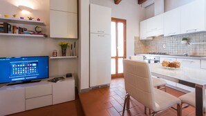 A modern kitchen with white cabinets, a built-in stove, and a dining area with a white chair. - Apartments Florence - Boboli Balcony Rooftop View Florence City Center (Firenze)