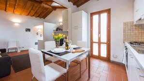 A dining area with a table set for two, white chairs, a vase with flowers, and a bottle of champagne. - Apartments Florence - Boboli Balcony Rooftop View Florence City Center (Firenze)