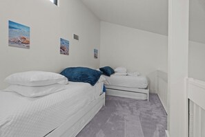 Un dormitorio con dos camas, ropa de cama blanca y alfombra gris.