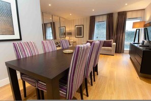 Een moderne hotelkamer met een zithoek, een bank, een bureau en uitzicht op zee.