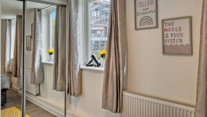 Habitación de hotel con un espejo grande, una ventana con cortinas y un cuadro con mensajes motivacionales.