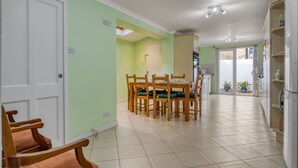A dining area with a table and chairs, a kitchen with cabinets, and a door leading to another room. - Spacious 4BR 3BA House Near Barons Court Station (London)