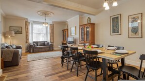 A dining area with a wooden table, black chairs, and a chandelier. - Spacious 4BR 3BA House Near Barons Court Station (London)