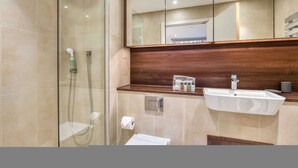 A modern bathroom with a glass shower enclosure, a wooden vanity, and a large mirror. - Modern 2 Bedroom Flat (London)