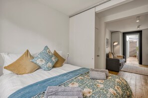 Une chambre à coucher avec un lit, des oreillers, une couverture et un canapé dans la pièce adjacente.