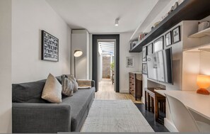 A modern living room with a grey sofa, a coffee table, a floor lamp, and a TV on a wall. - An Architect s Home - Vauxhall 1 Bed Apt - Zone 1 (London)