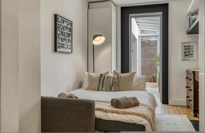 A bedroom with a bed, a bedside lamp, a chair, a dresser, and a framed picture on the wall. - An Architect s Home - Vauxhall 1 Bed Apt - Zone 1 (London)