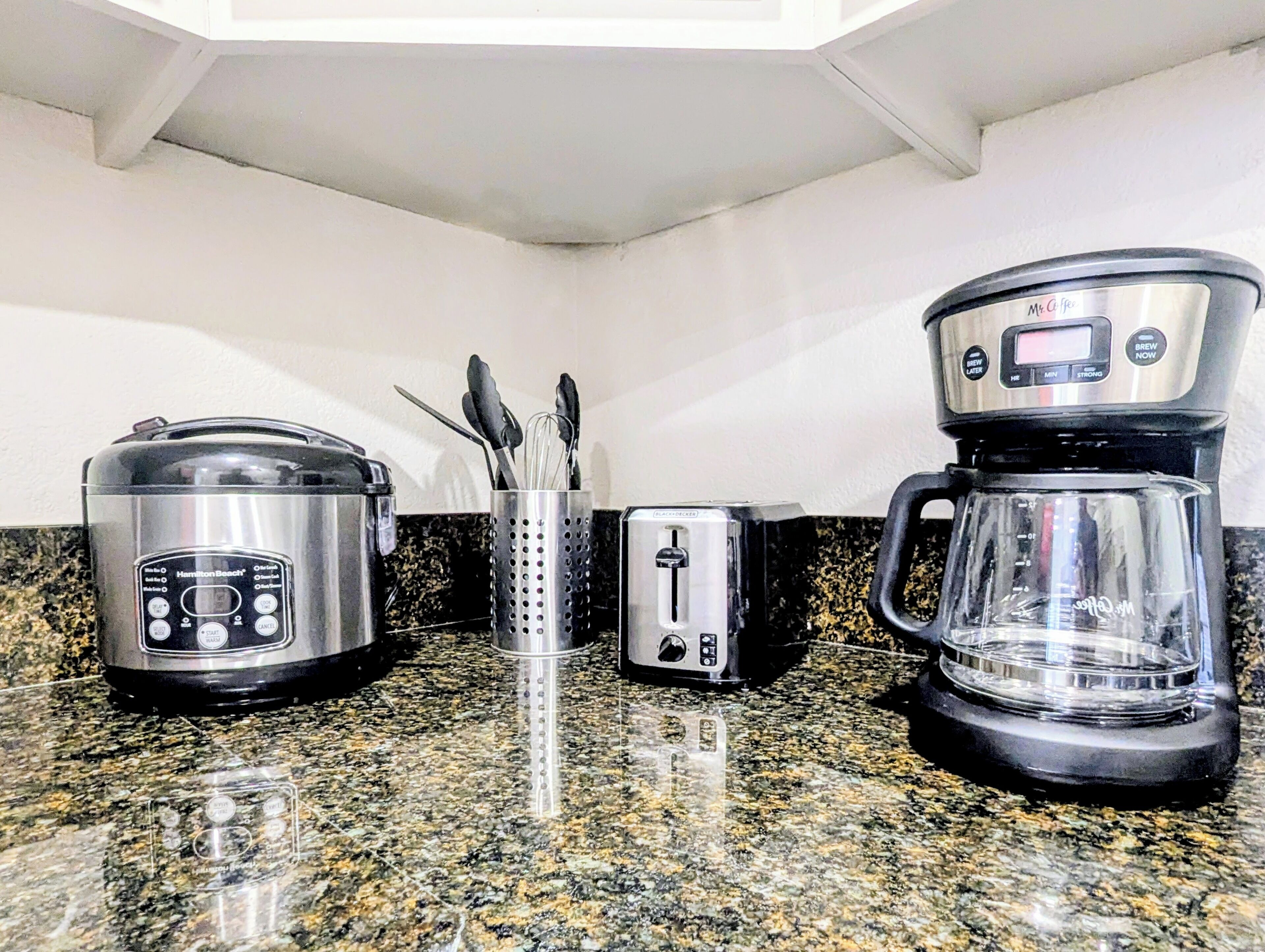 Een keuken met een Hamilton Beach slow cooker, een broodrooster en een Mr. Coffee koffiezetapparaat op een granieten aanrecht.