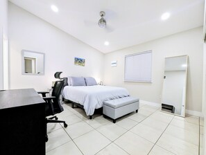 Habitació d'hotel amb llit, escriptori, cadira i un gran mirall.