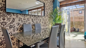 A modern dining area with a glass table, chairs, a large mirror, and a potted plant. - 107 Stonhouse Street Lovely 3-bed Clapham Common (London)