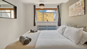A bedroom with a large bed, a window with curtains, a hanging light fixture, and a wall-mounted painting. - 107 Stonhouse Street Lovely 3-bed Clapham Common (London)