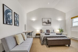 Een slaapkamer met een groot bed, een bank, een bureau en twee wandlampen.
