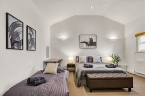 Een slaapkamer met twee bedden, een bureau en een groot raam.