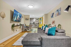 A modern living room with a grey sofa, a glass coffee table, and a flat-screen TV mounted on the wall. - Tranquil Apartment Southwark (London)