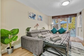 A modern living room with a sofa set, a potted plant, and artwork on the wall. - Tranquil Apartment Southwark (London)