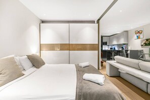 Ein modernes Hotelzimmer mit einem großen Bett, einer Sitzecke, einer Küchenzeile und einem Badezimmer.