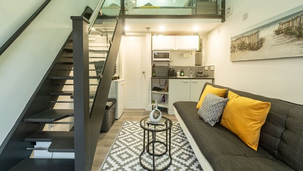 A modern apartment with a staircase, a kitchen, and a living area with a sofa and cushions. - Quirky Studio in Central Reading (Reading)