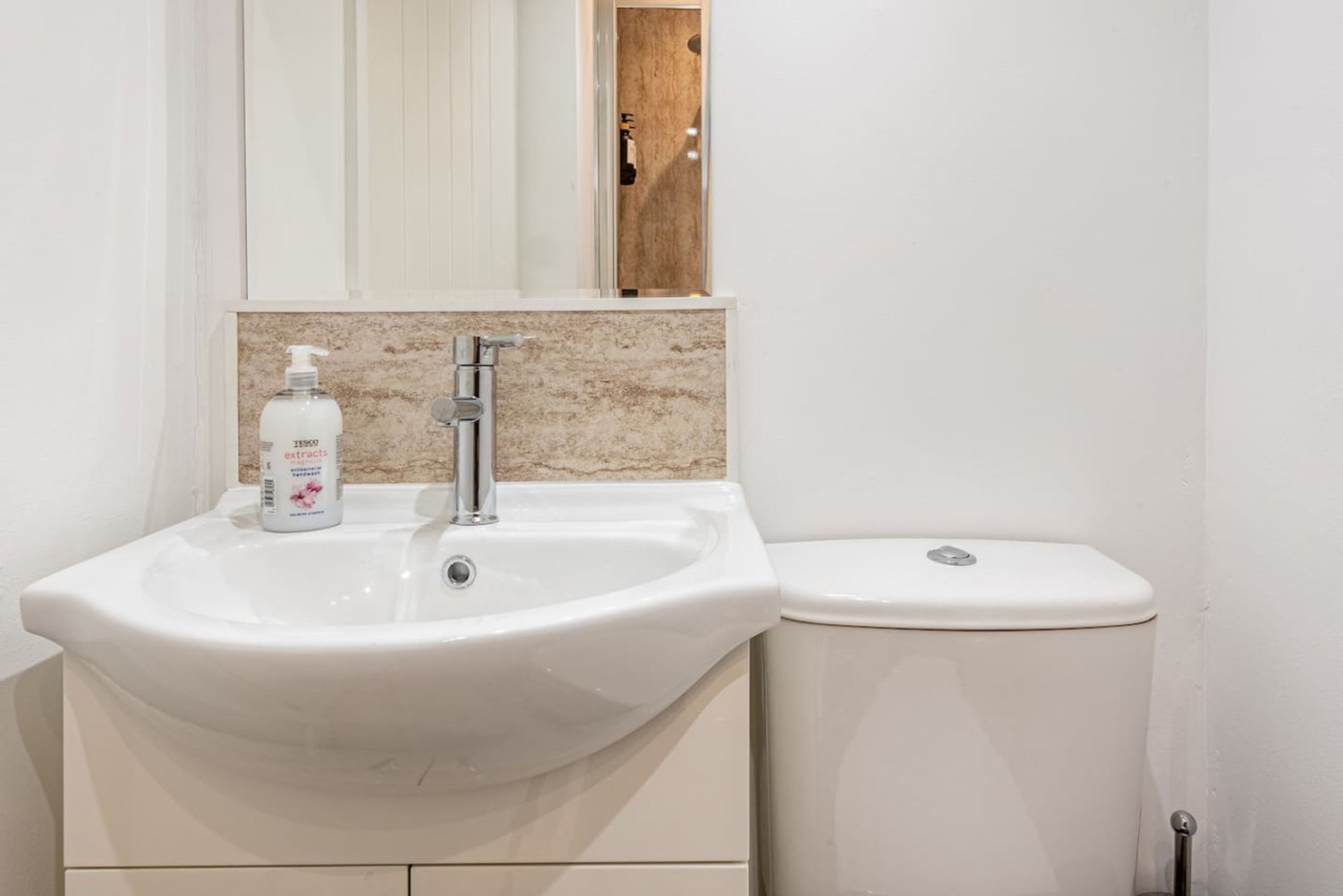 A bathroom with a white sink, a mirror, and a toilet.