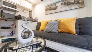 A modern living room with a grey sofa, a glass coffee table, a white spiral sculpture, and a painting on the wall. - Quirky Studio in Central Reading (Reading)
