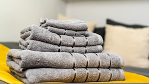 A neatly folded stack of towels on a bed with a yellow blanket. - Quirky Studio in Central Reading (Reading)
