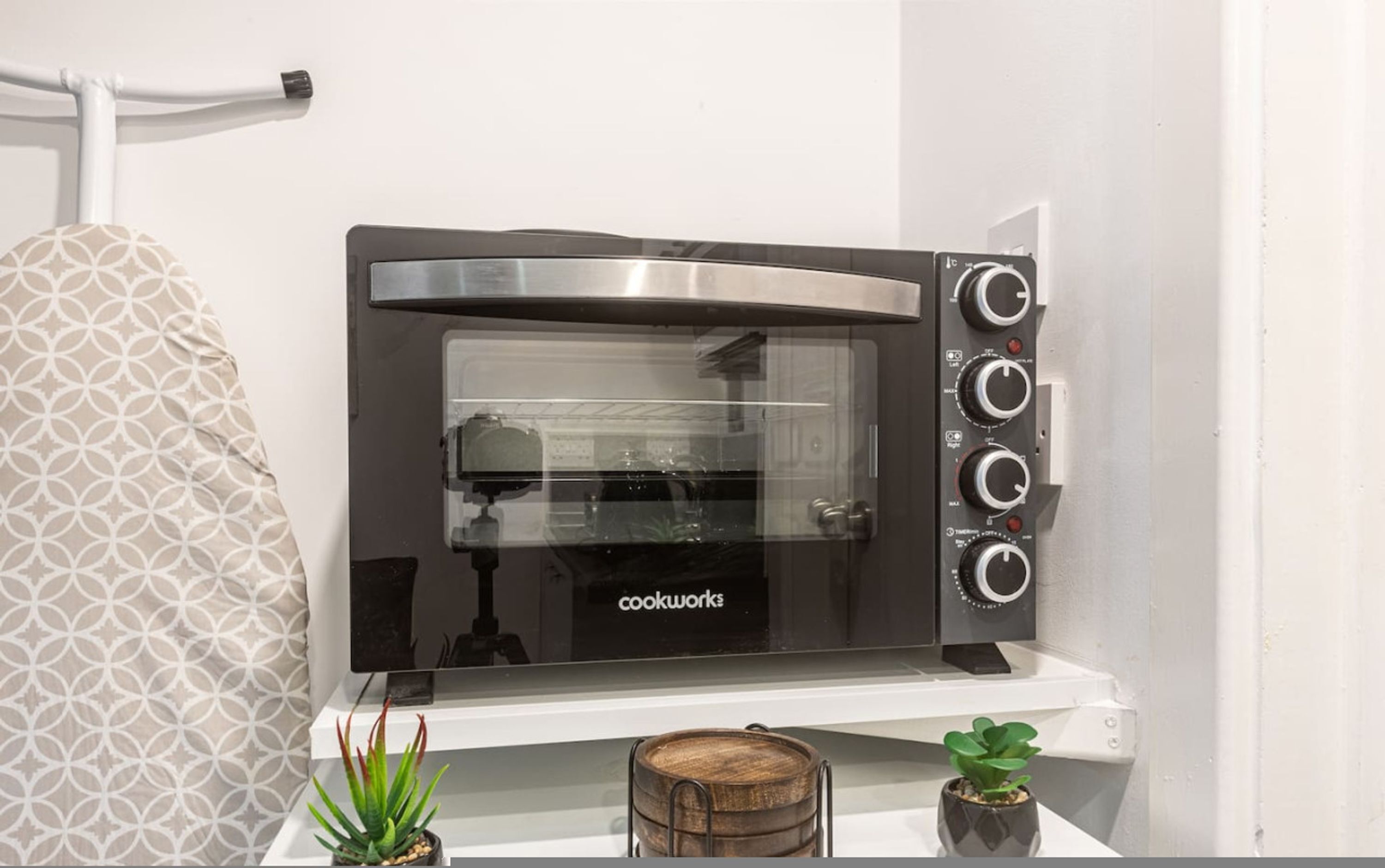 A compact, wall-mounted toaster oven with a control panel on the right side, placed on a white shelf.