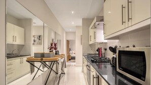 Una cucina moderna con mobili bianchi, un frigorifero in acciaio inossidabile e un forno a microonde nero.