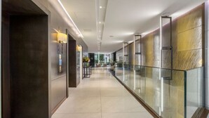 A modern hotel corridor with a glass railing, recessed lighting, and a view of the outdoors. - Luxe Creek Riverside Air-conditioned 2br 2bath (London)