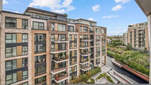 A multi-story residential building with balconies, a rooftop garden, and a water feature. - Luxe Creek Riverside Air-conditioned 2br 2bath (London)