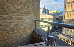 A brick wall, a metal railing, and a view of buildings in the distance. - Chic 2 Bed 2 Bath in Old Street (London)