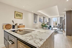 Een moderne keuken met een marmeren aanrechtblad, ingebouwde apparaten en een eethoek met uitzicht.