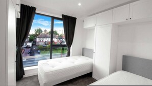 Een slaapkamer met een enkel bed, een garderobe en een raam met gordijnen.
