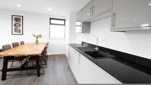 Een moderne keuken met een houten eettafel, witte kasten en een zwart aanrecht.