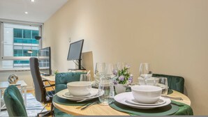 A dining table set with plates, bowls, glasses, and cutlery, with a computer monitor and lamp in the background. - 1 Bed 1 Bath Next to Vauxhall Station - Zone 1 (London)