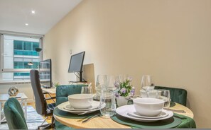 A dining table set with plates, bowls, glasses, and cutlery, with a computer monitor and lamp in the background. - 1 Bed 1 Bath Next to Vauxhall Station - Zone 1 (London)