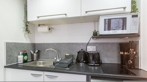 A kitchen with a sink, a microwave, a kettle, and a coffee maker. - Studio in Central Reading- Next to Town Centre (Reading)