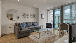 A modern living room with a sofa, coffee table, and dining area. - 1 Bed Sofa Bed- Nine Elms Station - Zone 1 (London)