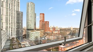 A high-rise building with a view of the cityscape through a window. - 1 Bed Sofa Bed- Nine Elms Station - Zone 1 (London)