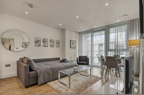 Ein modernes Wohnzimmer mit Sofa, Couchtisch, Fernseher und Essbereich.