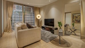A modern living room with a sofa, TV, and decorative plants. - Luxe Riverside Manhattan Studio (London)