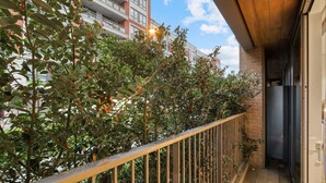 A balcony with a metal railing, a wooden ceiling, and a view of a building in the background. - Luxe Riverside Manhattan Studio (London)