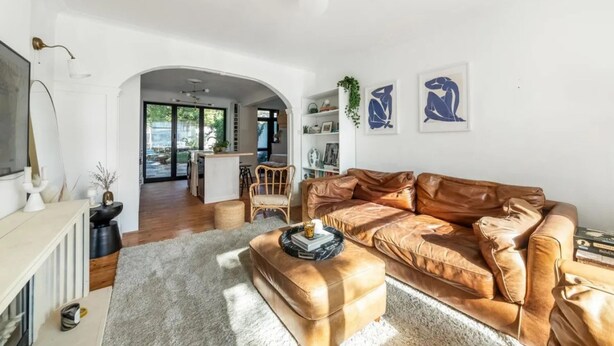 Una sala moderna con un sofá de cuero, una chimenea y un comedor al fondo.