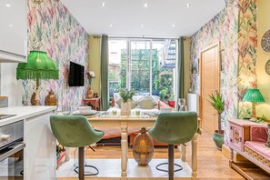 A modern living room with a sofa, chairs, a TV, and a dining area. - Charming 2bed Garden Apartment in Covent Garden (London)